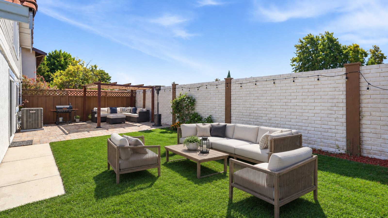Backyard at 35845 Tozier St with a pergola, paver patio, string lights and fresh lawn set up for entertaining