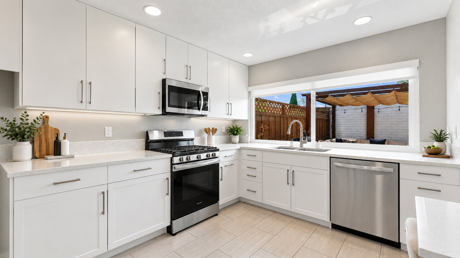 Remodeled kitchen with white shaker cabinets, quartz counters, stainless steel appliances and a garden window over the sink