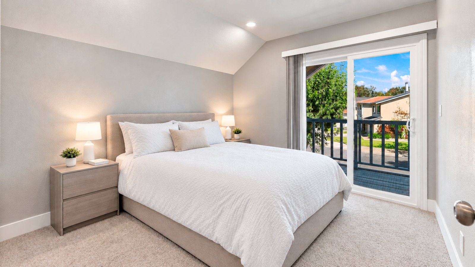Primary bedroom with vaulted ceiling and a sliding door opening to a private balcony